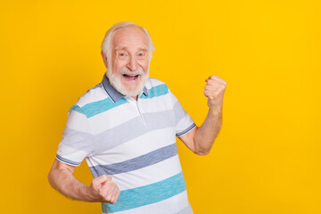 Portrait of attractive cheerful grey haired man rejoicing having fun isolated over vibrant yellow...