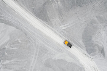 Limestone mining in open quarry, industrial truck with dump stone, aerial top view