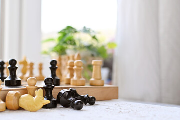 International Chess Day. Beautiful wooden chess stands on a white table against the background of...