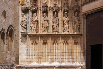 Gothic archivolt with lancet arches and sculptures of saints at the portal jamb of Castello d’Empuries city church, Catalonia in Spain