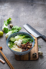 Japanese ramen soup with chicken, egg, chives and bok choy on concrete background.