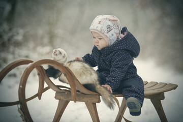 One year old baby on wooden toboggan with ferret friend - obrazy, fototapety, plakaty