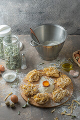 Freshly made tagliatelle pasta with eggs and flour on wooden board