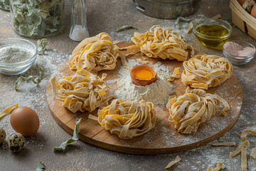 Freshly made tagliatelle pasta with eggs and flour on wooden board