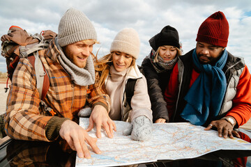 Multiracial friends examining map together during car trip