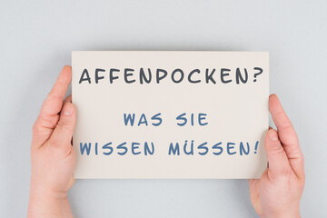 The words monkeypox, what you need to know, are standing in german language on a paper, outbreak of...