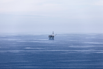 Blue waters of Bay of Biscay, covered with light ripples, merge with sky of almost same pale color and gas platform in the middle. Cape Matxitxako,  Basque Country, Spain