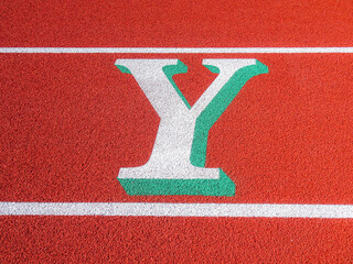 Two tone white and green letter Y painted on running track.