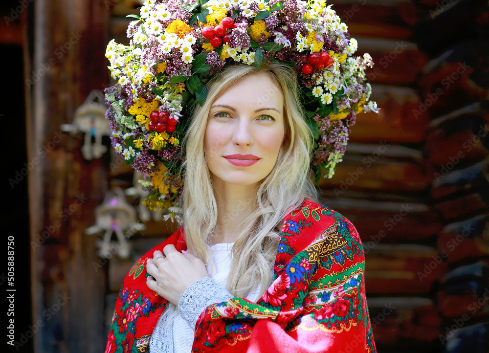 Wall mural a beautiful blonde girl with a smile in a flower wreath, a red scarf on her shoulders. Independence Day. Embroidery day. Glory to Ukraine! Ukrainian traditions concept