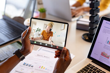 African american albino businessman briefing strategies to male coworker on digital tablet