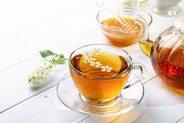 Useful spring tea with bird cherry in a transparent cup on a light background