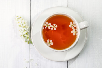 Useful spring tea with bird cherry in a white cup on a light background