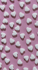 Vertical shot of seamless pattern of white hearts on pink background