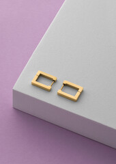rectangle earrings pair on white podium on purple background with copy space
