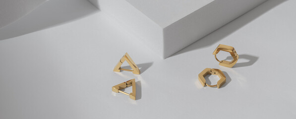 Panorama of triangle and hexagon shapes modern golden earrings on white background with copy space