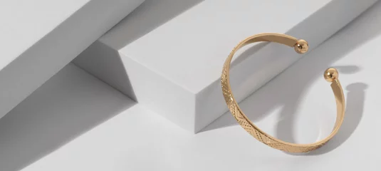 Poster Panoramic shot of a Modern gold bracelet with geometric pattern on minimalistic white background © Ayman Alakhras
