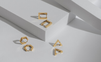 Top view of Three modern geometric shapes earrings pairs on white background with copy space