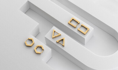 Top view of modern geometric golden earrings on geometric white background