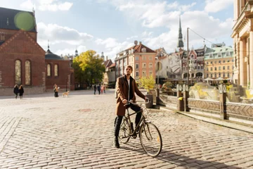Fototapete Rund Young man riding a city bike. Sustainable mobility transport New way of inclusive cities mobility. Green transportation. Sustainable climate neutral city goals. Green mobility and transportation © Girts