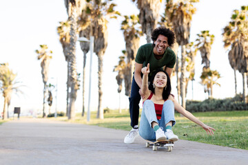 Fototapeta premium Beautiful couple having fun outdoors. Portrait of an excited young couple with skateboard...
