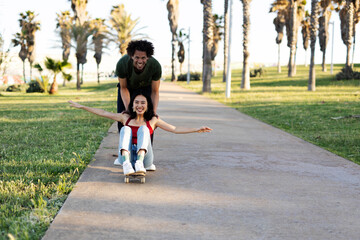 Beautiful couple having fun outdoors. Portrait of an excited young couple with skateboard...