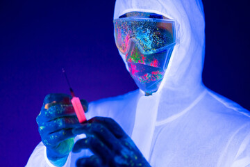 Doctor in ultraviolet neon light is holding COVID-19, сoronavirus vaccine and syringe using for...