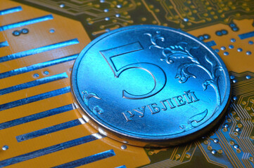 A coin with a face value of 5 rubles lies on a microcircuit. close-up. Translation of the inscription on the coin: 