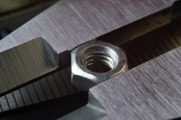 Accurate measuring tool caliper and metal ruler lie in place with nuts. close-up.