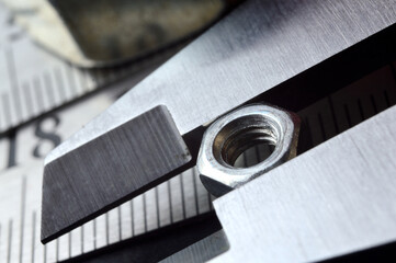 Accurate measuring tool caliper and metal ruler lie in place with nuts. close-up.