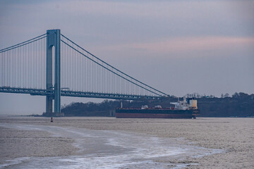 Cargo Ship at anchor in New York harbor near the Verrazano Narrows bridge with Staten Island in the...