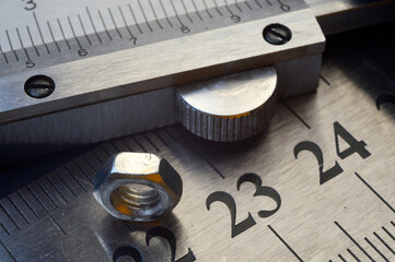 Accurate measuring tool caliper and metal ruler lie in place with nuts. close-up.