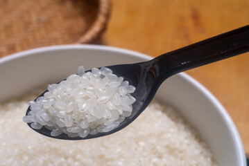 Close up of japanese rice in a black spoon. Japonica rice grains.
