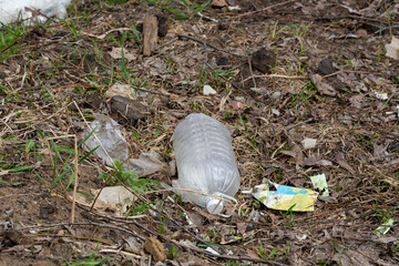 garbage bags and plastic bottles after the snow melts in spring. the concept of nature pollution by non-decomposing plastic