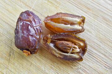 Organic fresh nutritious dried hurma dates medjool grains, on cutting board - obrazy, fototapety, plakaty