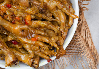 South African township delicacy, cooked chicken feet or walkie talkies with onion and sauce with rustic burlap cloth