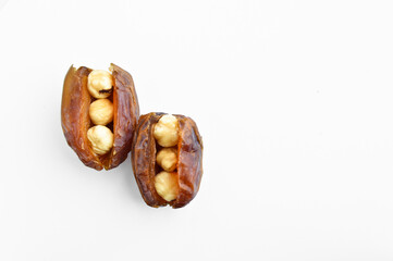 Dried hurma dates medjool grains, hazelnuts placed inside the date, on a white background - obrazy, fototapety, plakaty
