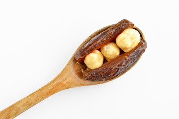Dried hurma dates medjool grains, hazelnuts placed inside the date, on wooden spoon - obrazy, fototapety, plakaty