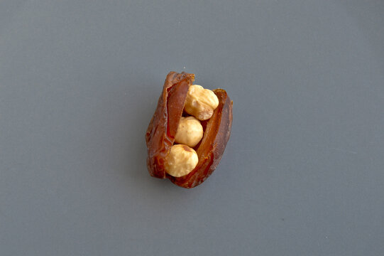 Dried hurma dates medjool grains, hazelnuts placed inside the date, in a gray plate