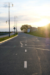 Beautiful cityscape. The setting sun shines on the road with markings. Curly lanterns along the road