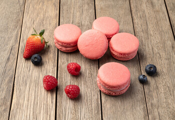 Berry macarons with strawberries, raspberries and blueberries over wooden table