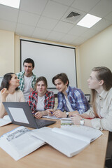 Vertical shot of a group of college students using laptop in class together