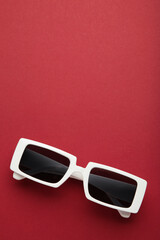 White sunglasses on red background, top view, flat lay, minimalistic concept of summer, vacation.