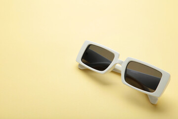 White sunglasses on yellow background, top view, flat lay, minimalistic concept of summer, vacation.