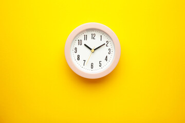 Pink clock on yellow background. Top view.