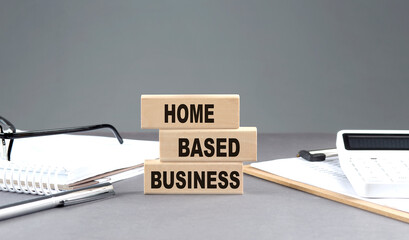HOME BASED BUSINESS text on wooden block with notebook,chart and calculator, grey background