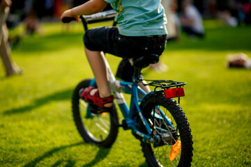 Fototapeta na wymiar summer background, kids riding hes first bike, green grass.