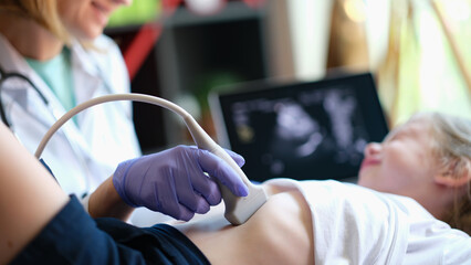 Doctor conducting ultrasound examination of internal organs of child in clinic