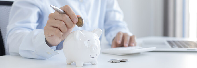Businessman's hand holds the money in the piggy bank for saving money for future use, saving money...
