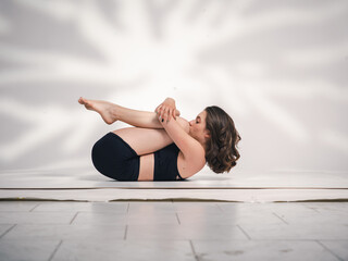 Fototapeta na wymiar One young Cacucasian woman, exercising yoga.