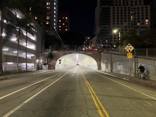 Fototapeta na wymiar LOS ANGELES, CA, OCT 2021: Anonymous person rides a bicycle towards brightly lit Third Street Tunnel in Downtown at night